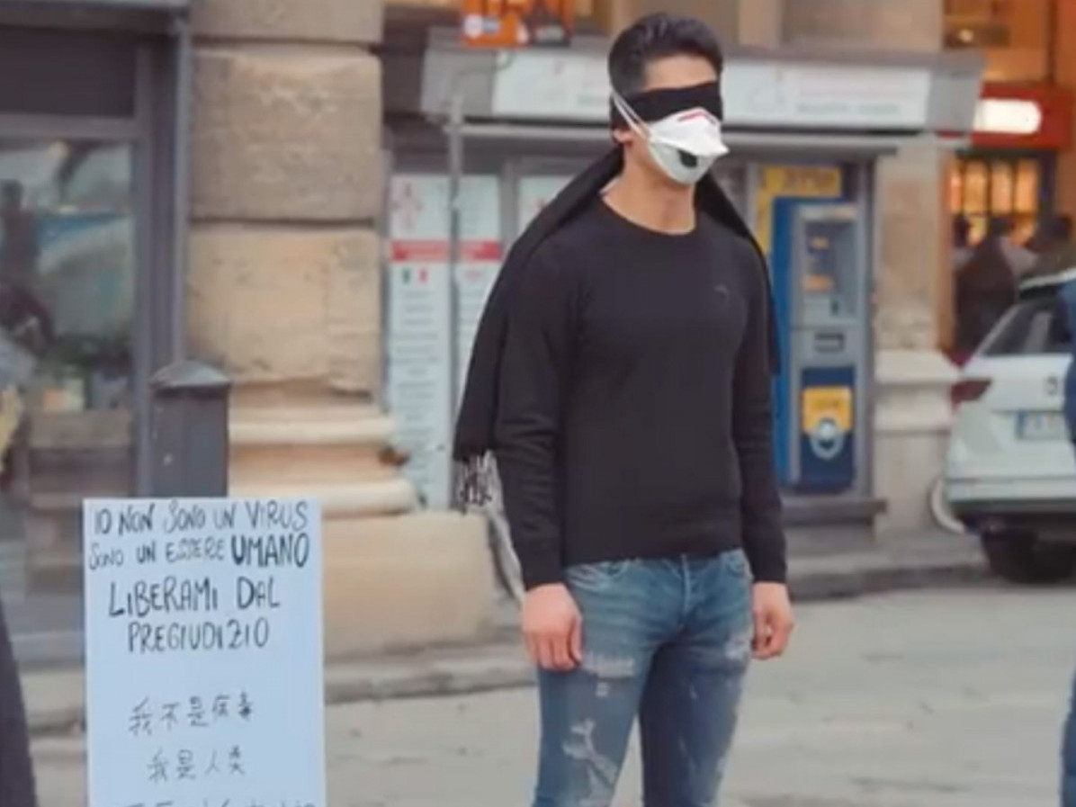 Хятад залуу “би вирус биш” гэсэн самбар барин гудамжинд зогсчээ