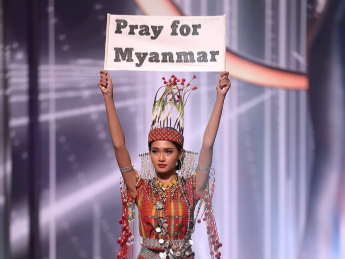 Мьянмарын гоо бүсгүй “Pray for Myanmar” бичигтэй самбар барьж, тайзан дээр алхлаа